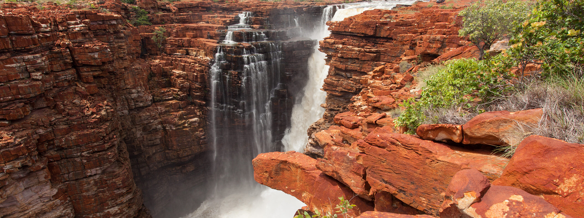 Waterfall cascading down a rocky cliff face with greenery